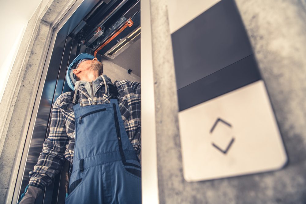 Professional Elevator Technician Fixing Lift Doors in Newly Build Residential Building.