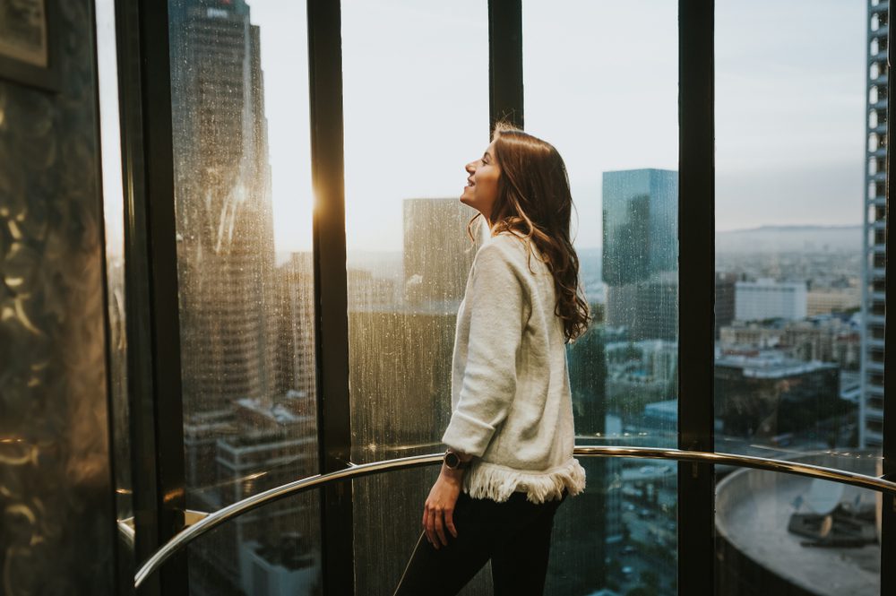 Young,Woman,In,A,Elevator,At,Window,Enjoying,The,City