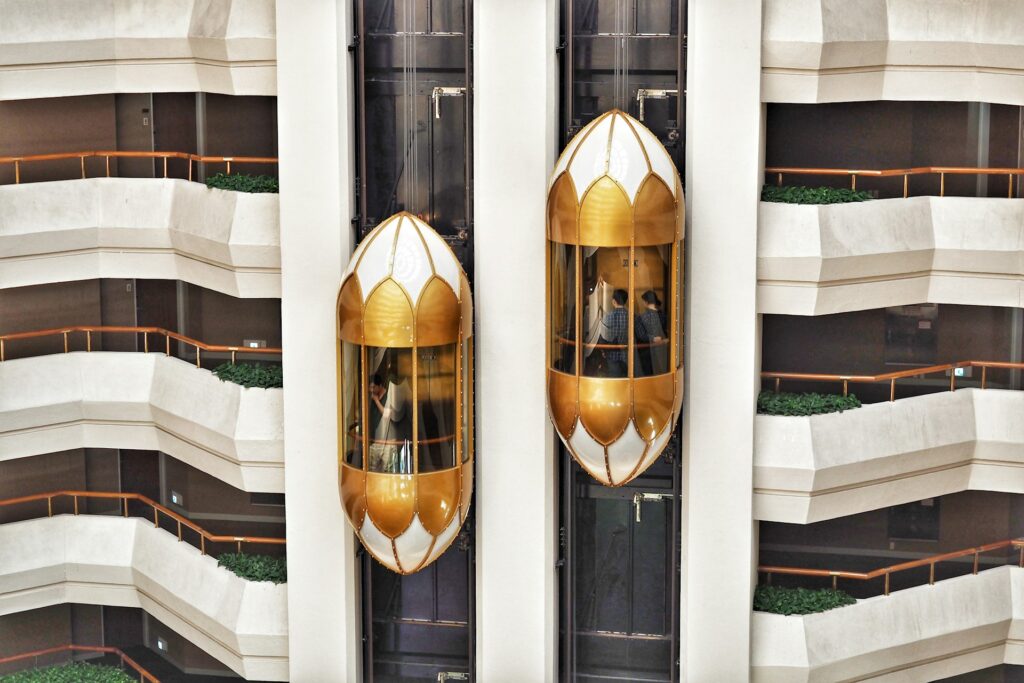 Two gold scenic lift cars rising through a hotel atrium