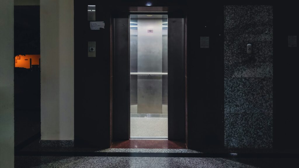 Passenger lift with doors open off a dark lobby